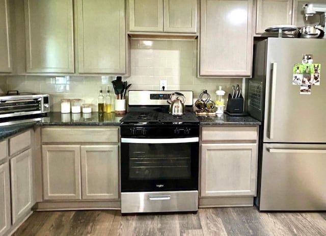 kitchen featuring cream cabinetry, appliances with stainless steel finishes, dark stone counters, and wood-type flooring