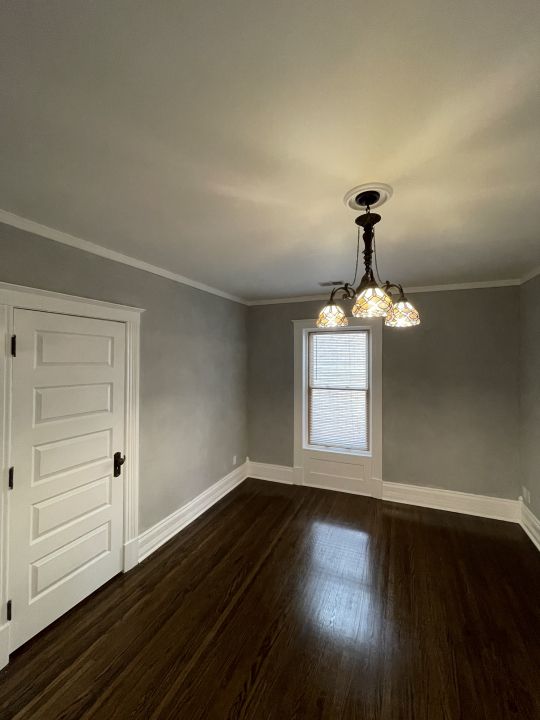 unfurnished room featuring ornamental molding, dark wood-type flooring, and an inviting chandelier