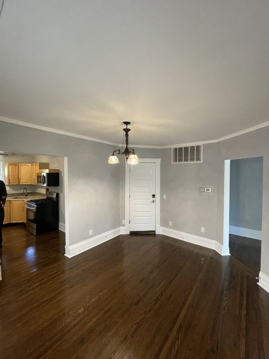 unfurnished living room featuring a chandelier, dark hardwood / wood-style floors, crown molding, and sink