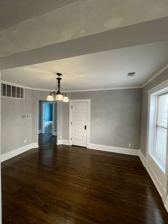 unfurnished dining area with dark hardwood / wood-style flooring, crown molding, and a chandelier