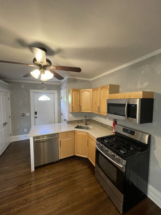 kitchen with light brown cabinets, dark wood-type flooring, sink, appliances with stainless steel finishes, and kitchen peninsula