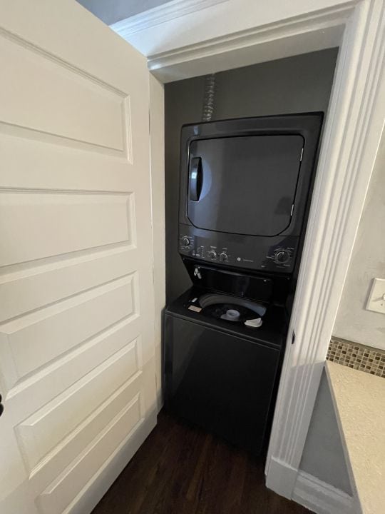 washroom featuring dark wood-type flooring and stacked washer / drying machine