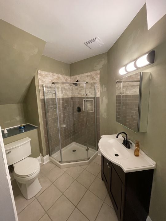 bathroom featuring tile patterned floors, vanity, toilet, and a shower with shower door