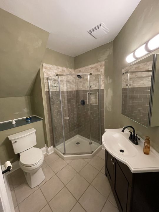 bathroom with tile patterned floors, vanity, a shower with shower door, and toilet