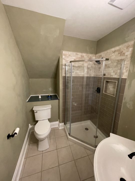 bathroom with toilet, tile patterned floors, and walk in shower