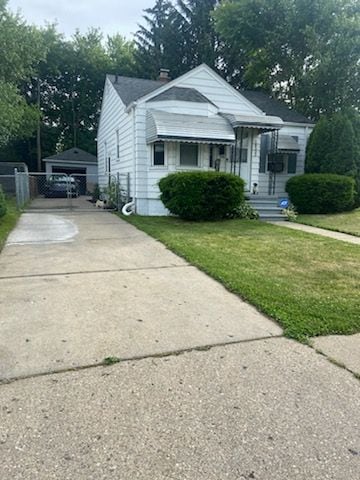 bungalow featuring a garage, an outbuilding, and a front lawn