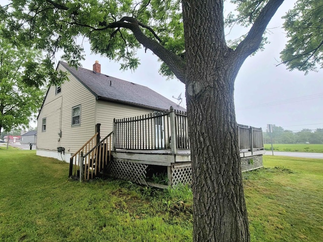 back of property featuring a shingled roof, a lawn, a chimney, and a wooden deck