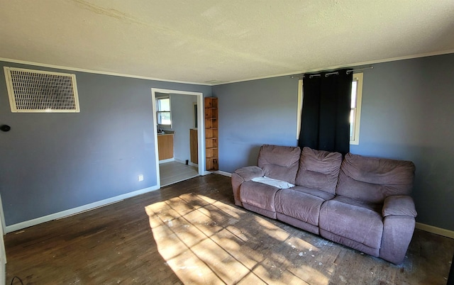 living room with baseboards, visible vents, wood finished floors, a textured ceiling, and crown molding