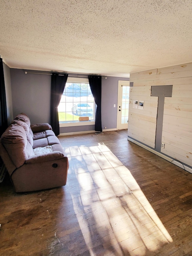 sitting room featuring baseboards, wood walls, a textured ceiling, and hardwood / wood-style floors