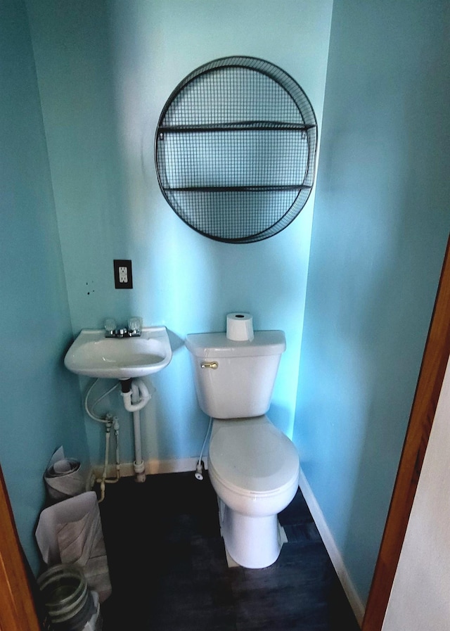 half bathroom featuring baseboards, a sink, toilet, and wood finished floors