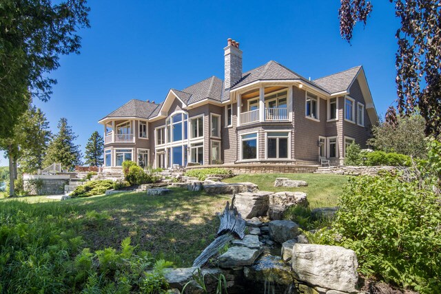 7545 Oyster Bay Dr Unit 4, Charlevoix, MI 49720 - rear view of property featuring a balcony, a chimney, a yard, and a shingled roof