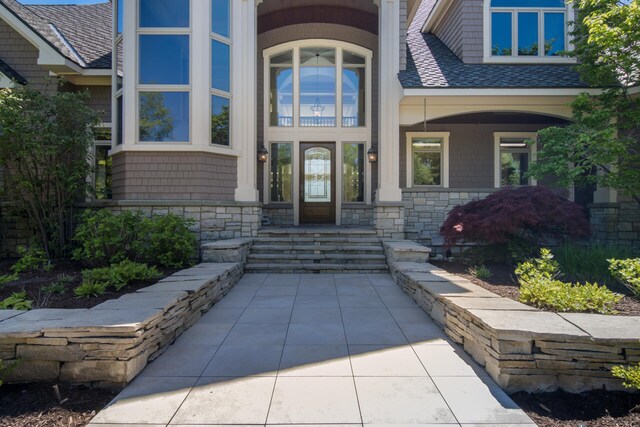 7545 Oyster Bay Dr Unit 4, Charlevoix, MI 49720 - property entrance with covered porch, roof with shingles, and stone siding