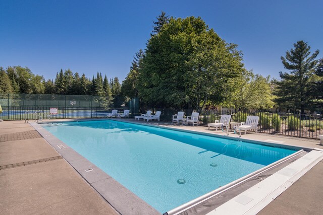 7545 Oyster Bay Dr Unit 4, Charlevoix, MI 49720 - community pool with a patio area and view of wooded area