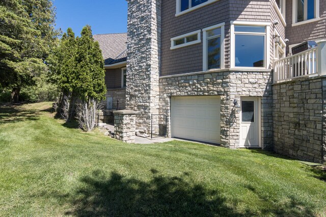 7545 Oyster Bay Dr Unit 4, Charlevoix, MI 49720 - view of side of property featuring stone siding, a garage, and a lawn