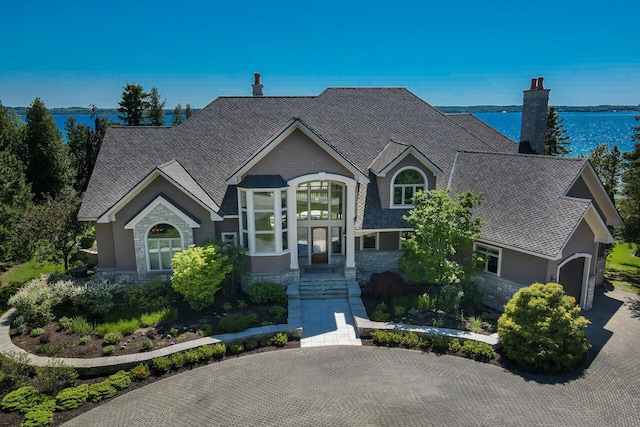 7545 Oyster Bay Dr Unit 4, Charlevoix, MI 49720 - view of front of property featuring stone siding, a chimney, a garage, and a shingled roof