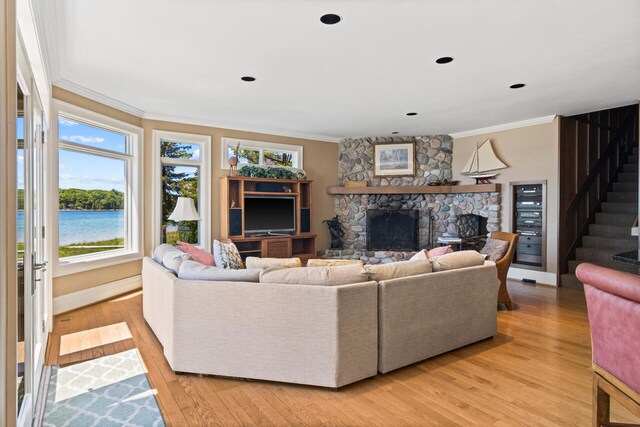7545 Oyster Bay Dr Unit 4, Charlevoix, MI 49720 - living room featuring ornamental molding, a fireplace, stairs, light wood-type flooring, and baseboards
