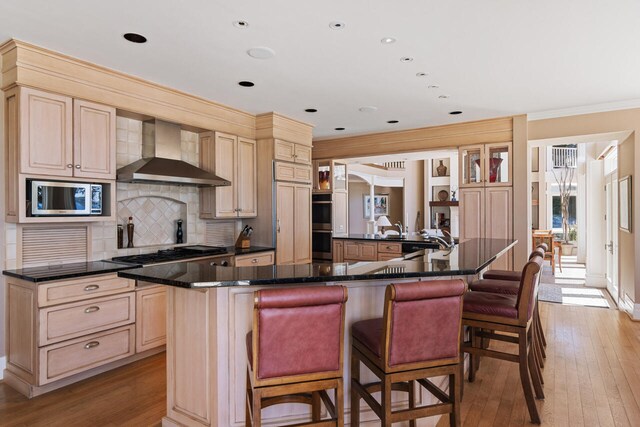 7545 Oyster Bay Dr Unit 4, Charlevoix, MI 49720 - kitchen with wall chimney range hood, stainless steel appliances, a kitchen breakfast bar, tasteful backsplash, and ornamental molding