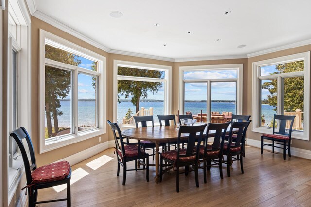 7545 Oyster Bay Dr Unit 4, Charlevoix, MI 49720 - dining room featuring a water view, hardwood / wood-style floors, baseboards, and ornamental molding