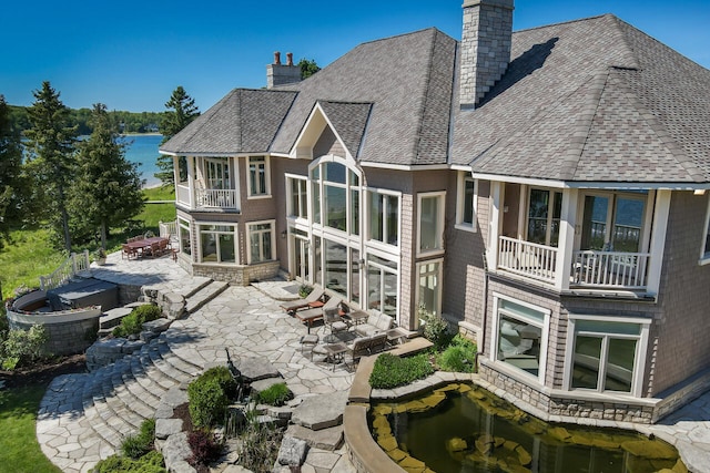 7545 Oyster Bay Dr Unit 4, Charlevoix, MI 49720 - rear view of property featuring a chimney, a balcony, a patio, roof with shingles, and a hot tub