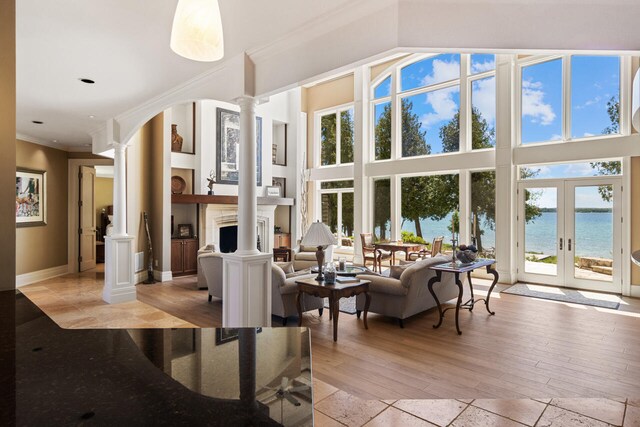 7545 Oyster Bay Dr Unit 4, Charlevoix, MI 49720 - living room with ornate columns, a water view, crown molding, a fireplace, and french doors