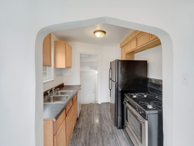 kitchen with gas range, sink, light brown cabinets, dishwasher, and hardwood / wood-style floors