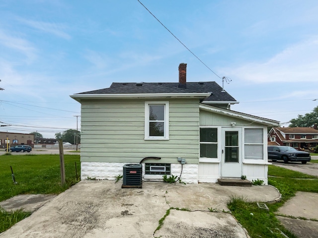 30430 Utica Rd, Roseville, MI 48066 - rear view of house featuring a patio area, a lawn, cooling unit, a chimney, and a shingled roof