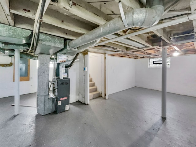 basement featuring electric panel and heating unit