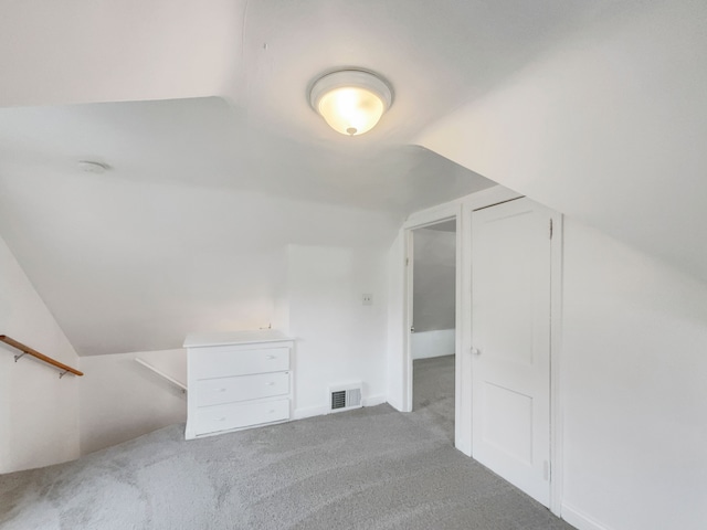 bonus room with light colored carpet and vaulted ceiling