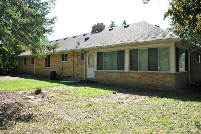 back of property featuring a lawn and central air condition unit