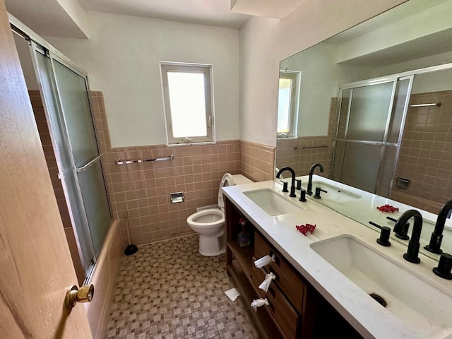 full bathroom featuring vanity, combined bath / shower with glass door, tile walls, and toilet