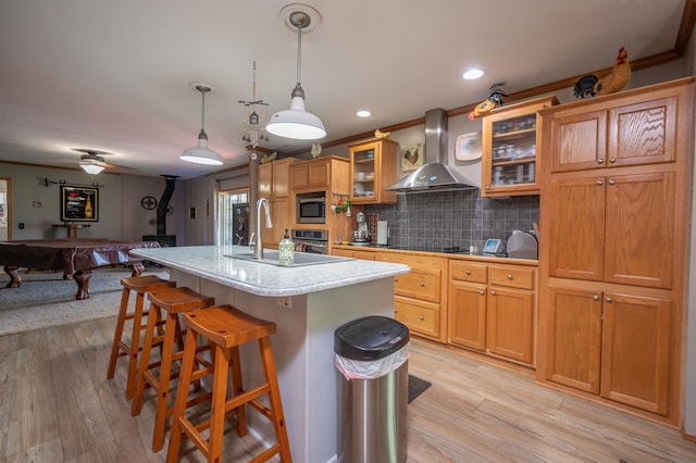 kitchen featuring light wood-type flooring, a center island with sink, wall chimney exhaust hood, and billiards