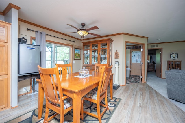 dining space with ceiling fan, light hardwood / wood-style floors, and ornamental molding