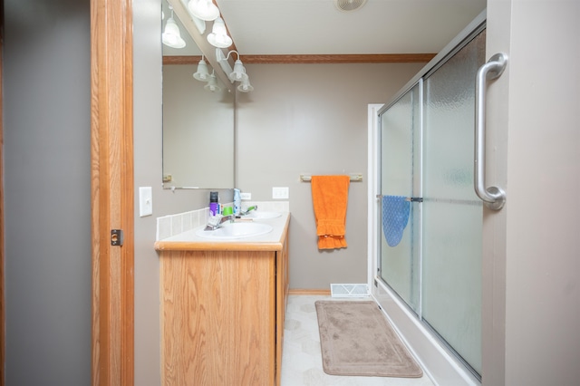 bathroom featuring vanity, a shower with door, and crown molding