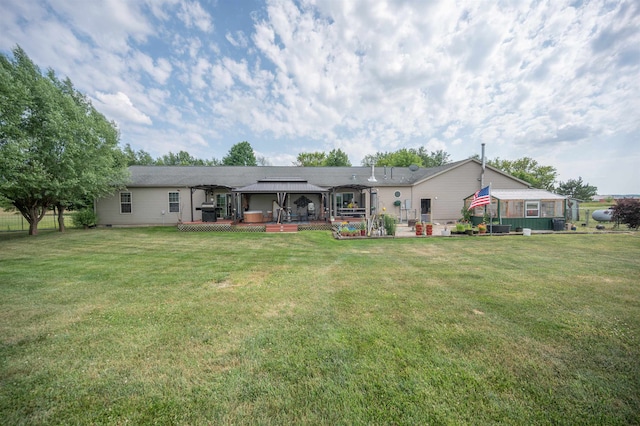 back of property featuring a gazebo, a deck, and a lawn