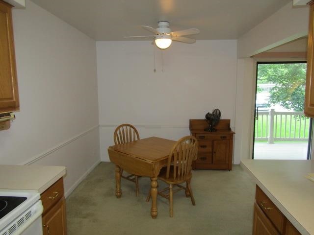 carpeted dining room with ceiling fan