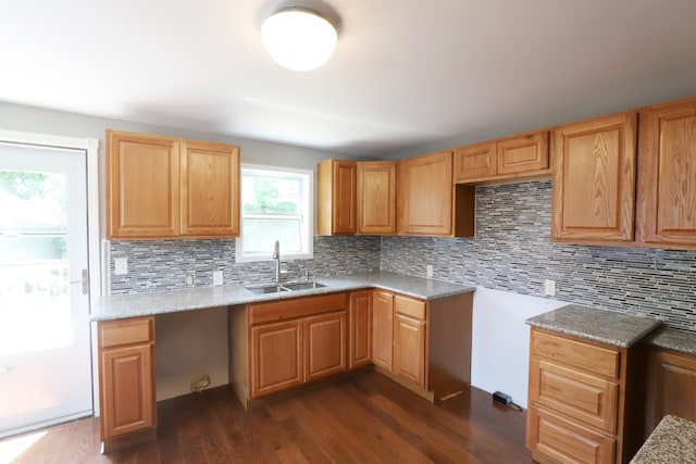 kitchen featuring decorative backsplash, dark hardwood / wood-style flooring, light stone countertops, and sink