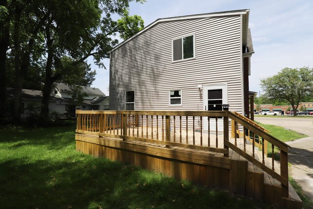 back of property featuring a lawn and a deck