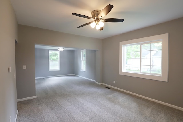 empty room featuring plenty of natural light, ceiling fan, and light carpet