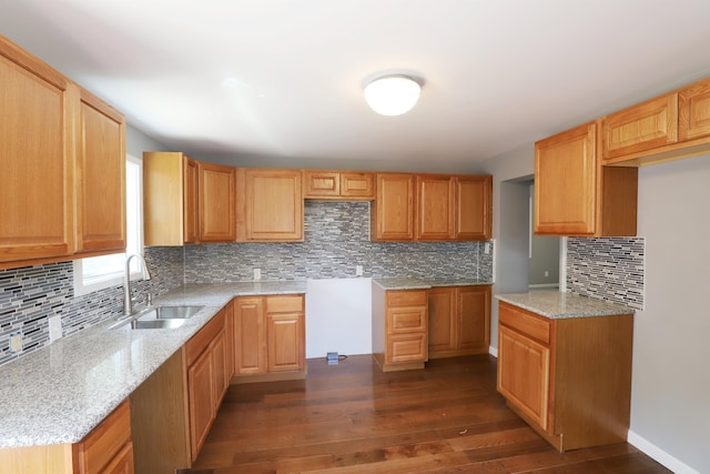 kitchen featuring dark hardwood / wood-style flooring, light stone countertops, sink, and tasteful backsplash