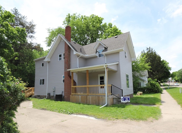 view of property exterior with covered porch, a yard, and central AC