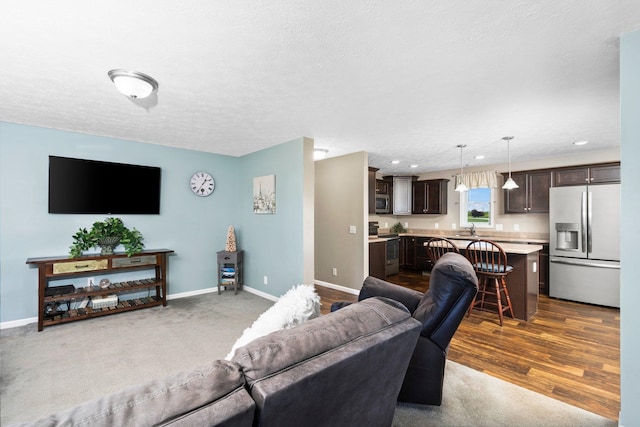 living room with a textured ceiling, hardwood / wood-style flooring, and sink