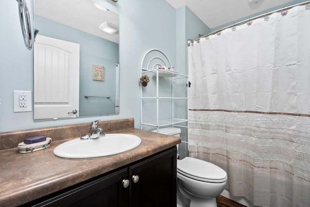 bathroom featuring a shower with curtain, vanity, toilet, and a textured ceiling