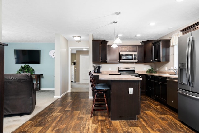 kitchen with pendant lighting, dark hardwood / wood-style floors, a kitchen island, and stainless steel appliances