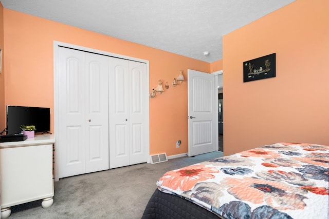 carpeted bedroom featuring a textured ceiling and a closet