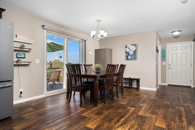 dining space featuring a textured ceiling, dark wood-type flooring, and a notable chandelier