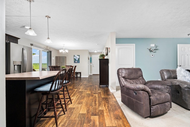 living room featuring dark wood-type flooring, a textured ceiling, and an inviting chandelier