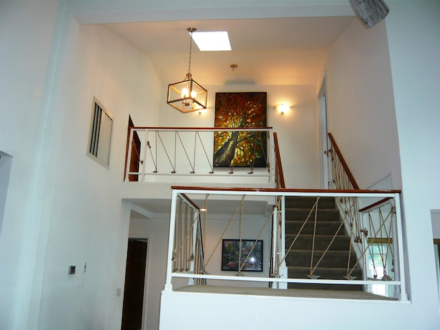 stairs featuring an inviting chandelier and a skylight