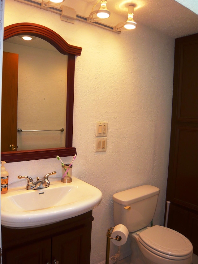 bathroom with vanity, a textured ceiling, and toilet