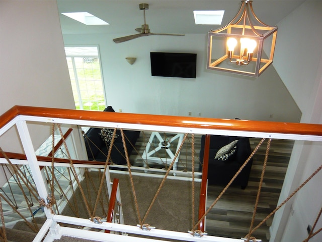 staircase featuring hardwood / wood-style flooring, ceiling fan with notable chandelier, and a skylight