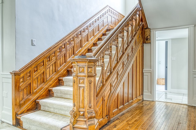 stairway with hardwood / wood-style floors and a high ceiling